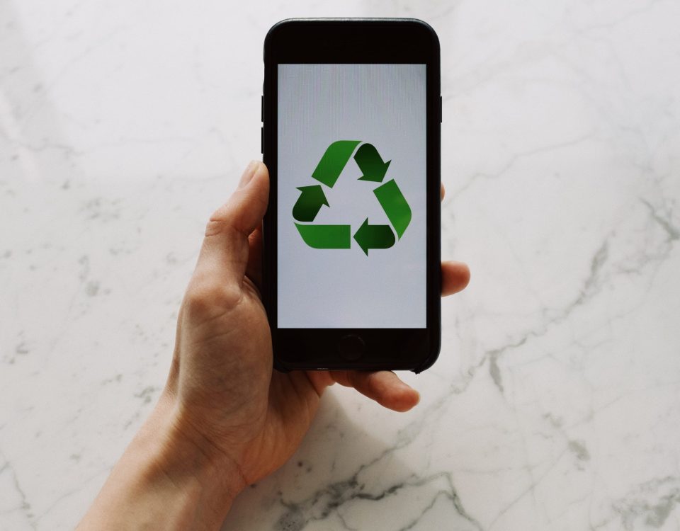 From above view of faceless person holding mobile phone with white screen and green recycle logo above marble surface