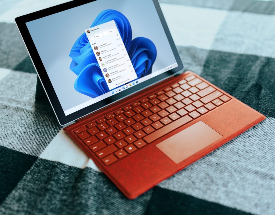 Red Surface laptop on a checkered bed by a window